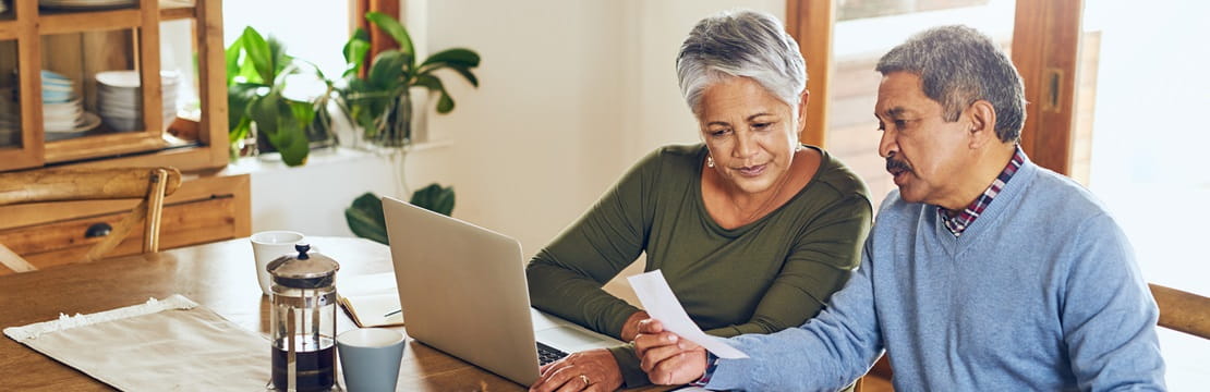 Woman and man sit at dining room table reviewing financial statements